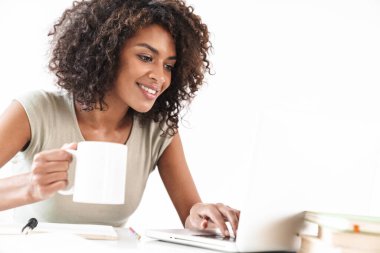 Gülümseyen genç Afrikalı kadın dizüstü bilgisayar kullanıyor.