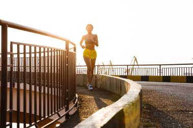 Spor giyim kuşağında deniz limanında koşan Asyalı bir kadının resmi