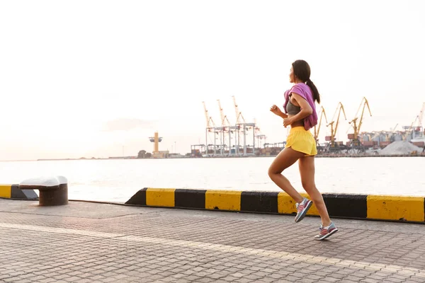 Bild av asiatisk kvinna i sportiga kläder som löper mot havet por — Stockfoto