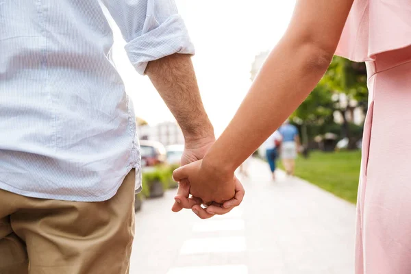 Couple walking by street outdoors holding hands of each other. — Stock Photo, Image