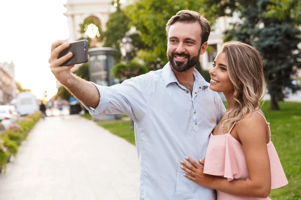 Paar, das draußen auf der Straße spaziert, macht ein Selfie mit dem Handy. — Stockfoto