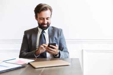 Ofiste çalışırken cep telefonunda yazan gülümseyen konsantre iş adamı görüntüsü