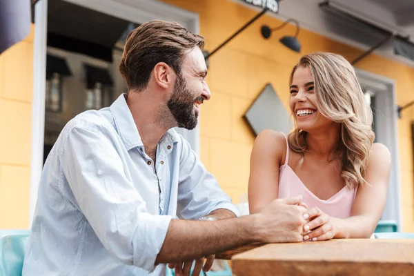 Unga kärleksfulla par utomhus sitter i caféet och pratar med varandra. — Stockfoto