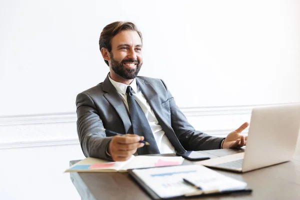 Image d'un homme d'affaires joyeux et séduisant travaillant sur un ordinateur portable au bureau tout en attendant avec impatience l'espace de copie — Photo