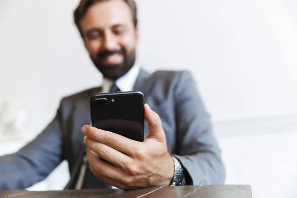 Image of bearded smiling businessman using cellphone while working in office — Stock Photo, Image