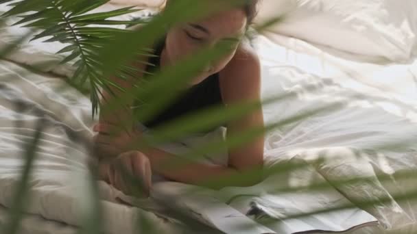 ベッドに横になって家で雑誌を読んでる可愛いアジア人女性を — ストック動画