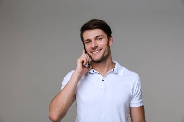 Neşeli yakışıklı genç adam cep telefonuyla konuşuyor..