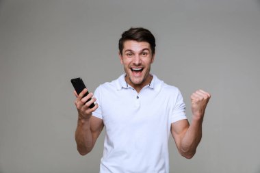 Cep telefonu kullanan duygusal genç adam kazanan hareketi yaptı.