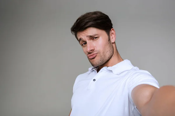 Homem posando isolado sobre fundo de parede cinza tirar uma selfie por câmera . — Fotografia de Stock