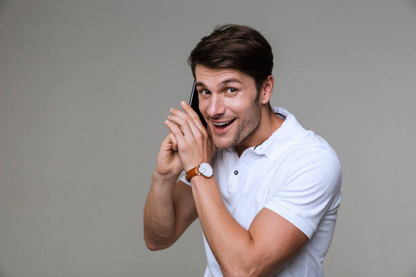 Веселый красивый молодой человек разговаривает по мобильному телефону
.