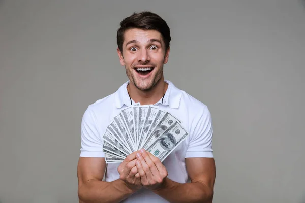 Positieve optimistische man poseert geïsoleerd over grijze muur — Stockfoto