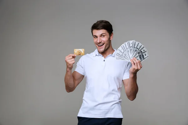 Optimistic man holding money and debit card. — Stock Photo, Image