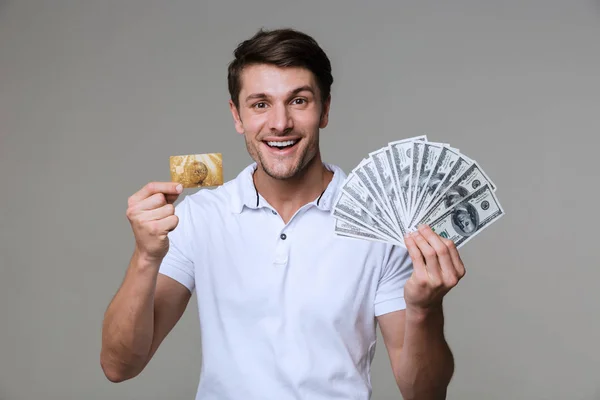 Optimistic man holding money and debit card. — Stock Photo, Image