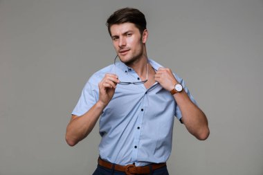 İş adamı gözlük tutarak gömleğini çıkarmaya çalışıyor.