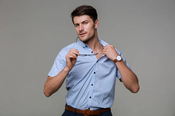 Бізнесмен намагається зняти сорочку, тримаючи окуляри — стокове фото