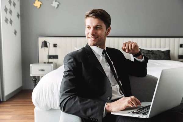 Image of happy young man sitting on sofa with laptop computer in — Stock Photo, Image