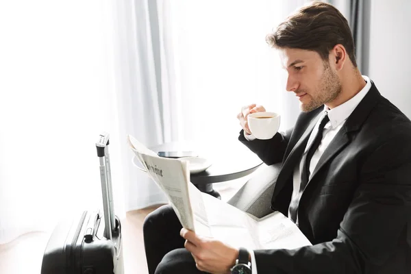 Концентрований серйозний бізнесмен вдома читає газету пити каву . — стокове фото