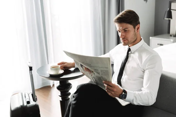 Gazete okuyan ve kahve içen güzel bir genç adam resmi. — Stok fotoğraf