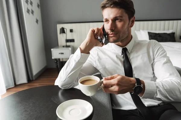 Image of masculine young man talking on smartphone and drinking — Stock Photo, Image