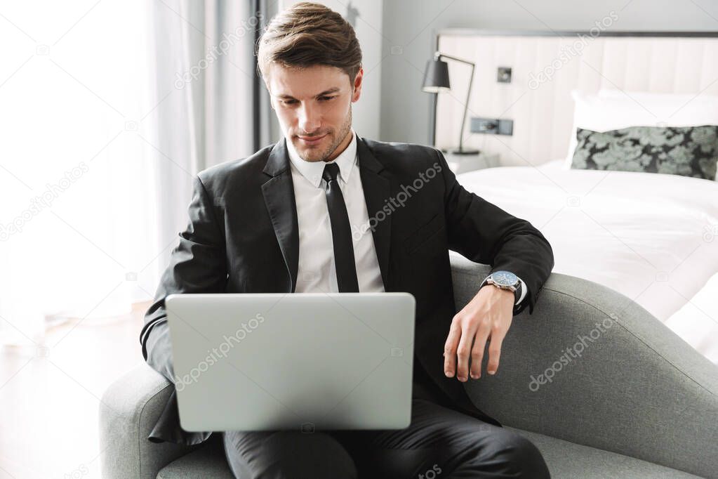 Image of caucasian young man sitting on sofa with laptop compute
