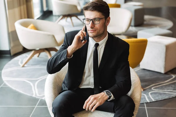 Photo of caucasian young man sitting in hotel hall with smartpho — Stock Photo, Image