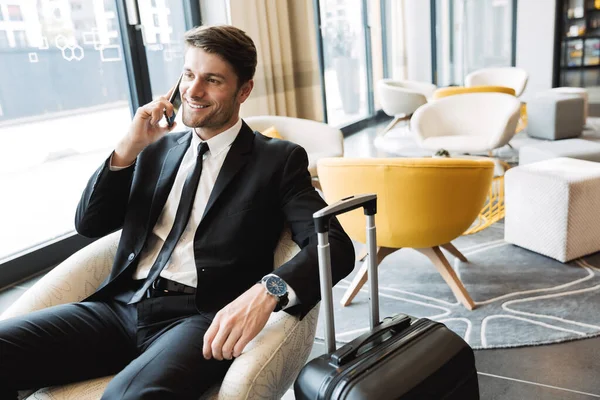 Foto de joven hombre de negocios caucásico hablando en el teléfono inteligente mientras —  Fotos de Stock