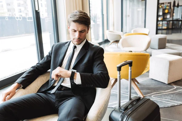 Photo of serious young businessman looking at his wristwatch whi — Stock Photo, Image