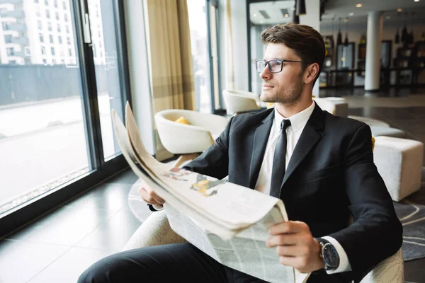 Retrato de un joven hombre de negocios elegante sentado en el sillón y re — Foto de Stock