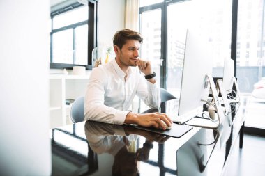 Masada oturup çalışan memnun iş adamı imajı.