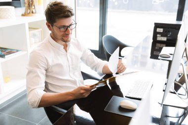 Elinde kağıtlar olan genç bir iş adamı resmi.