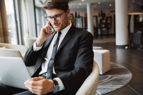 Retrato de empresario atractivo utilizando ordenador portátil y tal —  Fotos de Stock