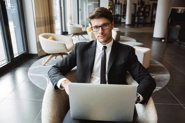 Foto di sicuro uomo d'affari che indossa occhiali da vista utilizzando il computer portatile c — Foto Stock