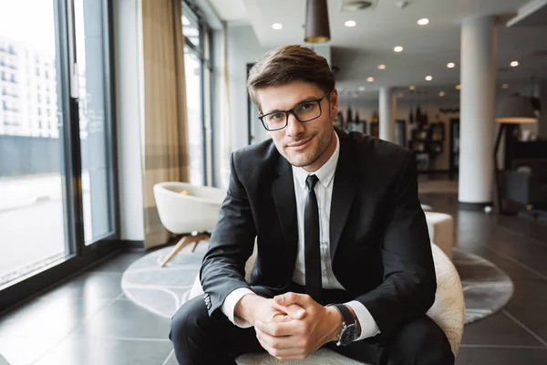 Photo of young businessman wearing eyeglasses sitiing on armchai — Stock Photo, Image