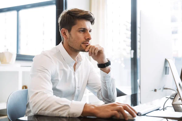 Imagem de um homem de negócios sério sentado à mesa e a trabalhar — Fotografia de Stock