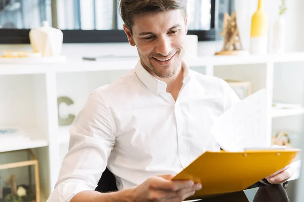 Imagen del feliz hombre de negocios sosteniendo portapapeles con documentos mientras trabaja en la oficina — Foto de Stock