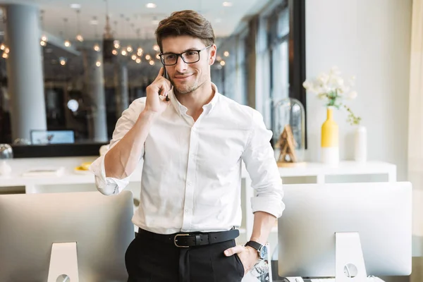 Imagen del exitoso hombre de negocios hablando por teléfono celular mientras —  Fotos de Stock