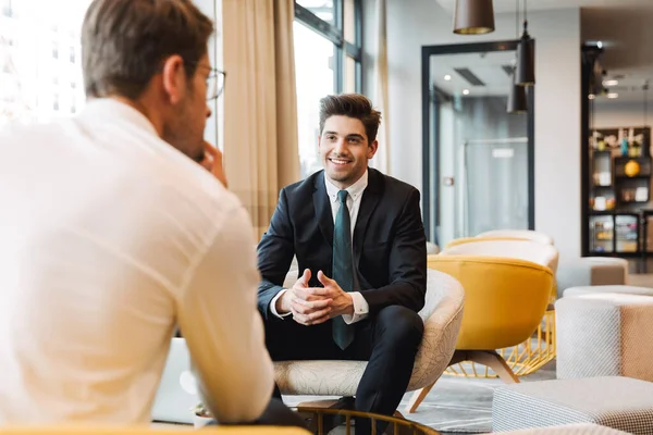 Счастливые коллеги-бизнесмены в помещении офиса бизнес-центра беседуют друг с другом . — стоковое фото