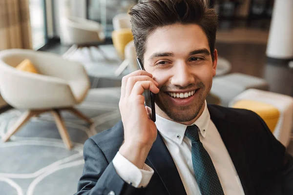 Empresario optimista alegre en el interior de la oficina del centro de negocios hablando por teléfono móvil . —  Fotos de Stock
