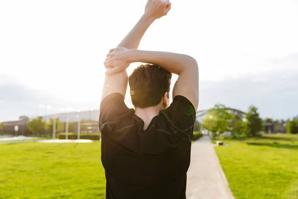 Beeld van een jonge man uit te werken en te rennen op groen park buiten in de ochtend — Stockfoto