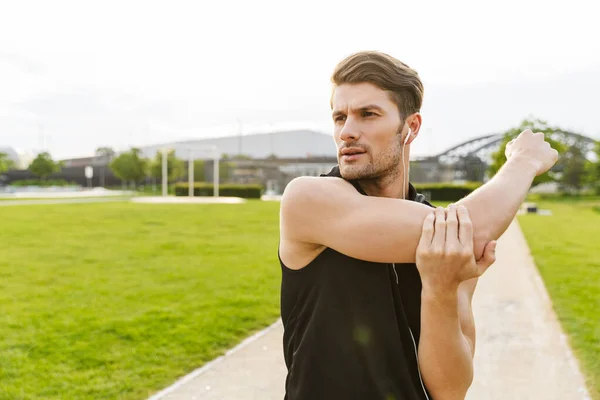 Imagem do homem muscular trabalhando com fones de ouvido e correndo em — Fotografia de Stock