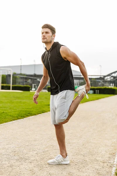 Imagen del hombre caucásico haciendo ejercicio con auriculares y corriendo en — Foto de Stock