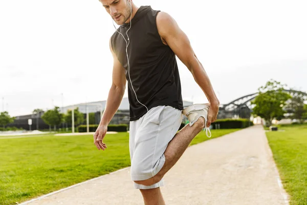 Obrázek zdravého muže, jak cvičí se sluchátky a běží na g — Stock fotografie
