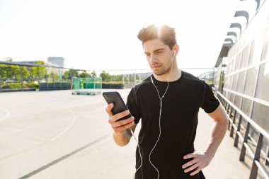 Spo 'da dururken elinde cep telefonu tutan esmer adamın portresi.