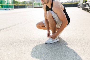 Spor ayakkabılarını bağlayan kaslı bir adamın görüntüsü.