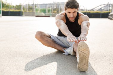 Spor sahasında sabah sporu yapan kaslı bir adamın görüntüsü.