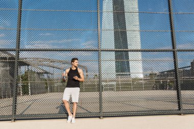 Cep telefonu ve su şişesi tutan kaslı adamın portresi.