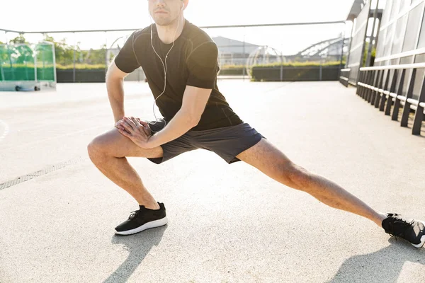 Imagem de homem bonito usando fones de ouvido treinamento em esportes groun — Fotografia de Stock