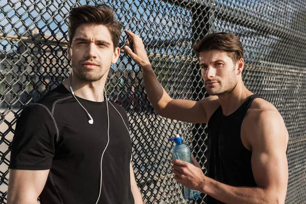 Φωτογραφία των μυϊκών ανδρών σε αθλητικά ρούχα κρατώντας μπουκάλι νερό κατά τη διάρκεια — Φωτογραφία Αρχείου