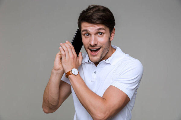 Веселый красивый молодой человек разговаривает по мобильному телефону
.