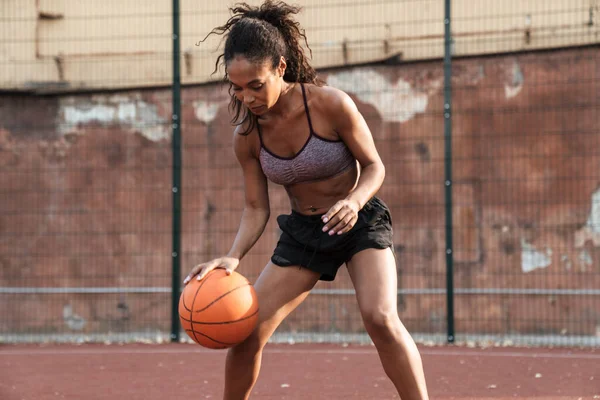 Imagen de una mujer afroamericana concentrada jugando baloncesto — Foto de Stock